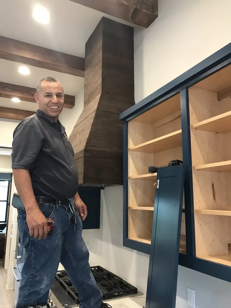 Eduardo, owner of ET Handyman Service, beside a finished kitchen cabinet and wood range hood he installed